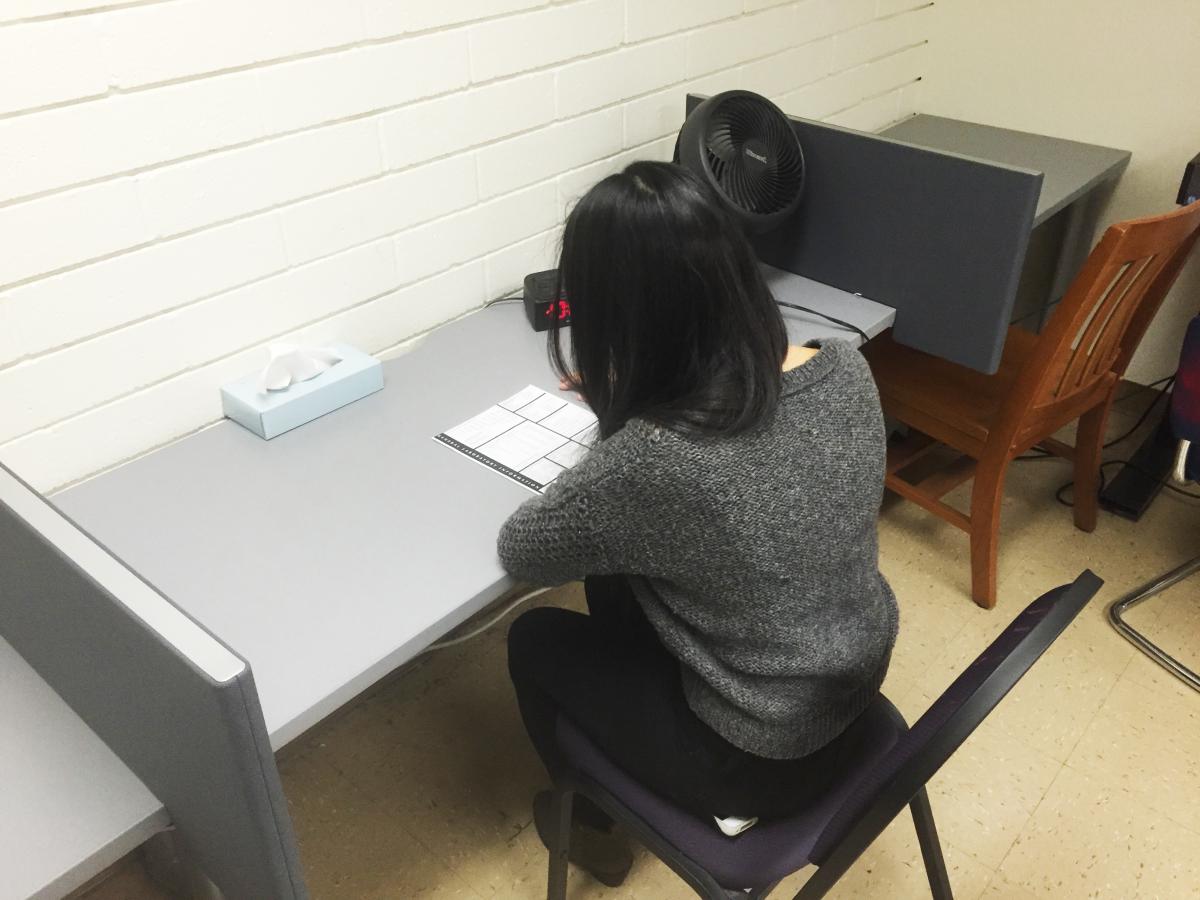 A student is sitting down, facing away, taking an exam in the Wheeler proctoring suite.