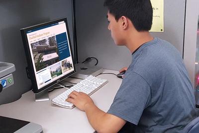 Student sitting at a computer applying for services.